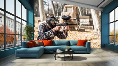 A man with a gun playing paintball. Wall mural