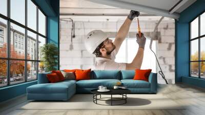 electrician installer with a tool in his hands, working with cable on the construction site. Wall mural