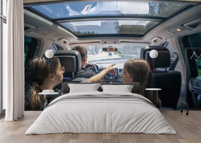 Little girls sitting in back seat of car during family trip. Wall mural