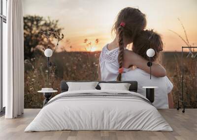 Two little sisters in a field at sunset. Wall mural