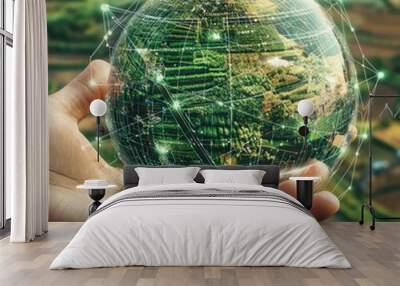 A hand holds a glowing globe with a green background, symbolizing the interconnectedness of our planet. Wall mural