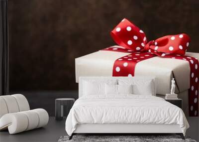 A single gift box wrapped in brown paper with a red polka dot ribbon on a dark background. Wall mural