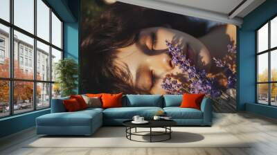 A young woman with her eyes closed lies in a field of lavender, bathed in the golden light of the setting sun. Wall mural