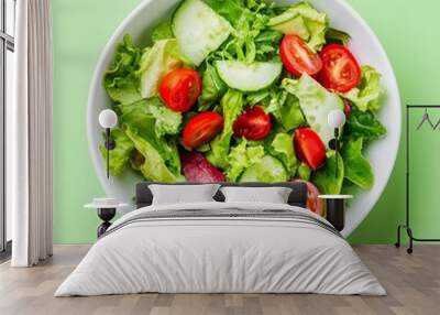 Fresh green salad with cherry tomatoes and cucumber in a white bowl on a green background. Wall mural