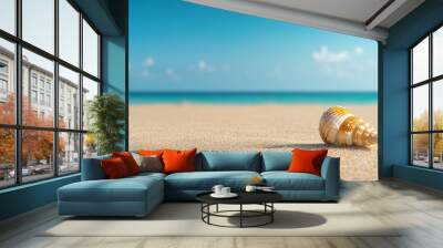 Seashell on a sandy beach with a blurred background of blue sky and ocean. Wall mural