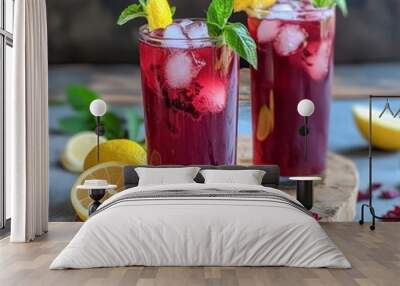 Two glasses of iced hibiscus tea with lemon and mint on a wooden board. Wall mural