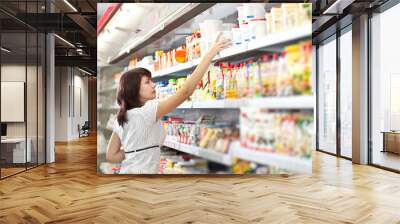 Young woman in the supermarket choose food Wall mural