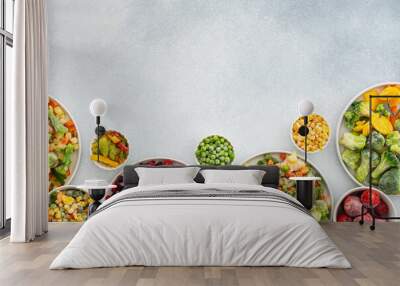 Preparing fresh vegetables in summer for winter, various frozen vegetables and berries in plates on a gray background, top view, copy space Wall mural