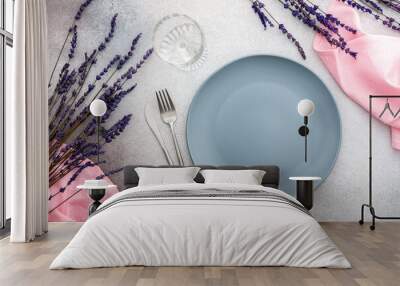 Table setting, empty plate with napkin and cutlery on a gray-pink concrete background, top view of the served table decorated with dry lavender flowers Wall mural