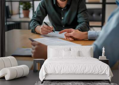 Two individuals participate in a crucial business meeting, with one signing a contract, depicting decision-making and agreement Wall mural