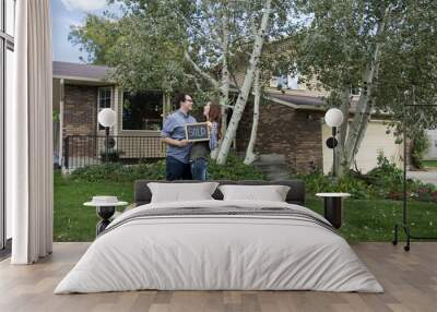 couple and dog in front of new home staring at each other with sold sign Wall mural