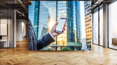 A man in suit is holding smartphone in an urban setting, surrounded by modern skyscrapers. scene conveys sense of professionalism and connectivity Wall mural