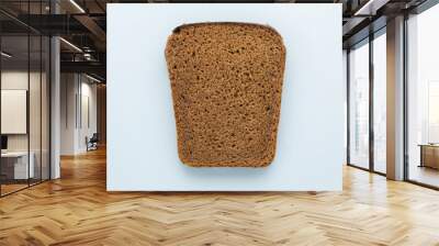 Single slice of brown rye bread on blue background. Top view. Wall mural