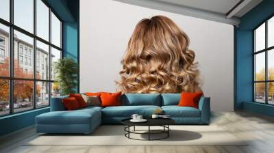 Female hairstyle with long curls on the head of a blonde with a back view on a gray background. Wall mural