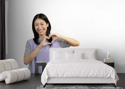 Asian young woman with bright smile making heart symbol shape with hands, Symbol of love and romance, Give each other cuteness and create smiles for each other, Positive thinking concept. Wall mural