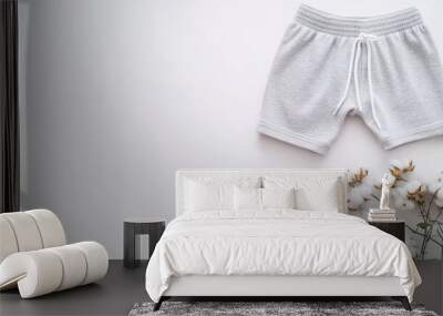 Minimalist composition of gray men's boxer shorts alongside cotton flowers on a clean, white surface for stylish casual elegance Wall mural