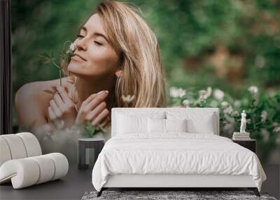 Woman smells white flowers lying on the lawn Wall mural