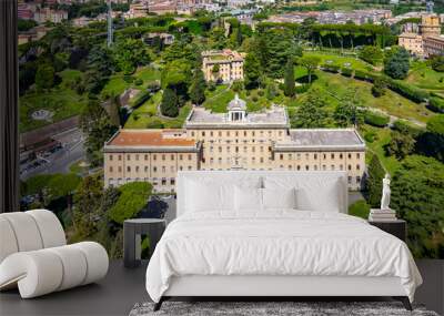 The Governorates Palace in Vatican is showcased from above, featuring its stunning architecture surrounded by meticulously manicured gardens and lush greenery, set against the city's backdrop. Wall mural