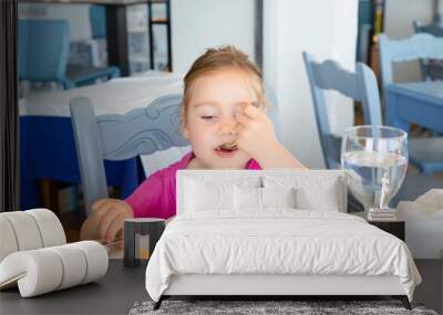 portrait of four years old blonde girl eating Spanish paella rice from white plate, left handed, sitting in restaurant Wall mural