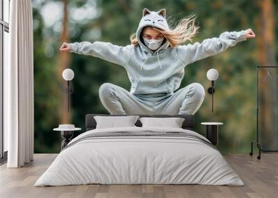 Teenage girl in a cat's grey hoodie jumping on all fours on nature background. Quadrobing, all fours activity and quads subculture concept. Lifestyle shot for poster, demonstration Wall mural