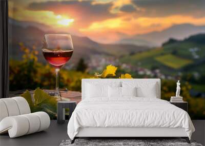 A glass of wine is sitting on a table in front of a beautiful mountain landscape Wall mural