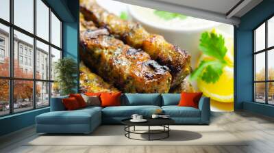 A plate of few skewers of meat with a side of sauce Wall mural