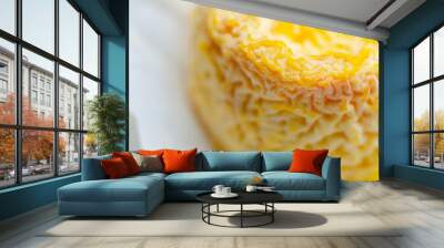 A yellow cheese is sitting in a paper wrapper Wall mural