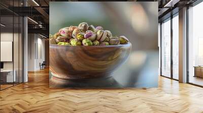 Pistachio dry fruit in wooden bowl on glass table Wall mural