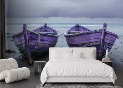 Telling tales of a life at sea two ancient violet boats lie side by side on the beach Wall mural