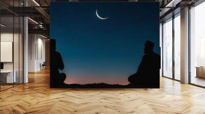 Panoramic banner with silhouette of two praying Muslim men in traditional clothing against a night sky with a crescent moon. Religious men praying alone among mountains during Ramadan Wall mural