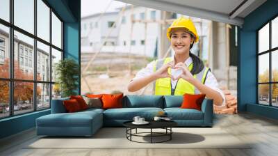 beauty woman hand love sign dressing as engineer worker builder in construction site background Wall mural