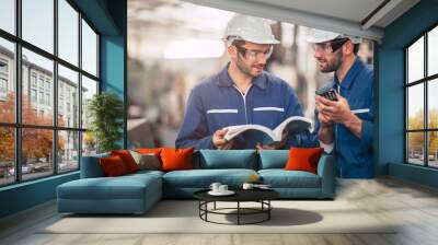 Engineer team talking together teach and learn engineering technical about using machine with open instruction manual text book in factory workplace. Wall mural