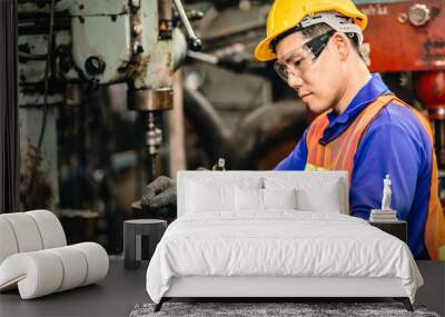 Engineer worker checking and replace a drill bit of metal drilling machine in heavy industry factory. Wall mural