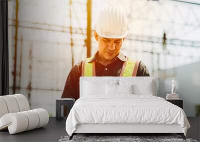 Foreman builder engineer worker using tablet computer to check building floor plan at construction site. Wall mural