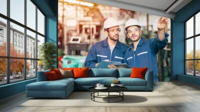 Two engineer worker working together with safety uniform and white helmet to work in industry factory handle tablet. Wall mural