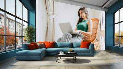 young woman happy smiling typing at laptop computer relax indoor at home living room. people leisure with modern technology device Wall mural