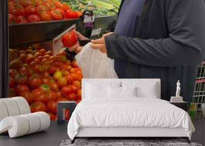 Fat man using bioplastic bag selecting tomatoes at groceries store Wall mural