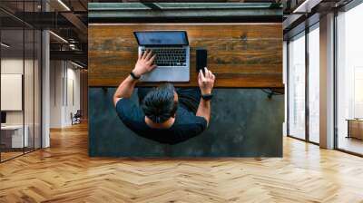 High angle view of Asian man working on smartphone and laptop Wall mural