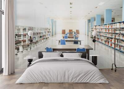 An empty college library with open spaces, blue chairs and book stacks. A modern light and airy building. Wall mural