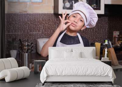 Cheerful little chef showing good taste while holding baked bread in the kitchen  Wall mural