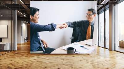 Mature Asian businessman leader and young coworker making a fist bump dealing project. Business success and teamwork concept. Wall mural