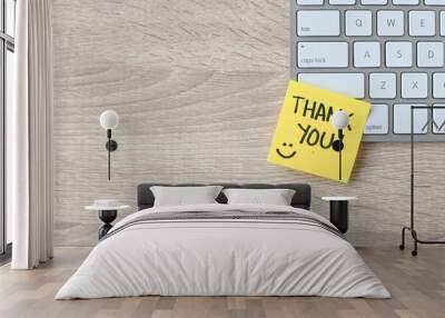 Top view of words thank you written on sticky note on keyboard over wooden background.  Wall mural