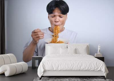 Young Asian man enjoying eating fried spicy noodles with fork Wall mural