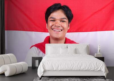 Young Man Smiling And Looking At Camera Over Indonesia Flag Background Wall mural