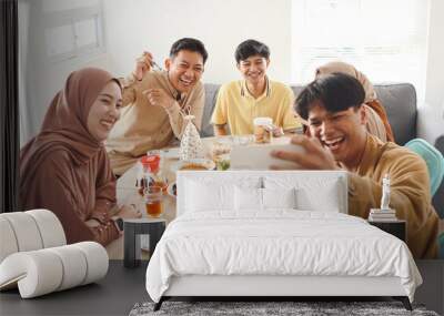 Young muslim friends taking selfie or video call during eating together. Iftar ramadhan and eid mubarak celebration Wall mural