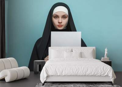 Young Nun Holding a White Sign Mockup on Solid Light Blue Background for Religious and Informational Designs. Wall mural