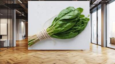 bunch of spinach leaves wrapped in twine on a white surface with water droplets Wall mural