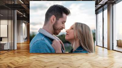 woman grabbing her boyfriend's jacket with a beautiful sunset in the background Wall mural