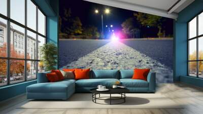 Focus on city road with blurred police car red and blue lights in the distance, crime and accident concept Wall mural