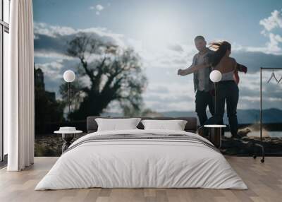 A happy couple enjoys a dance on a sandy beach during their holiday, under a clear blue sky with scenic landscapes around. Wall mural